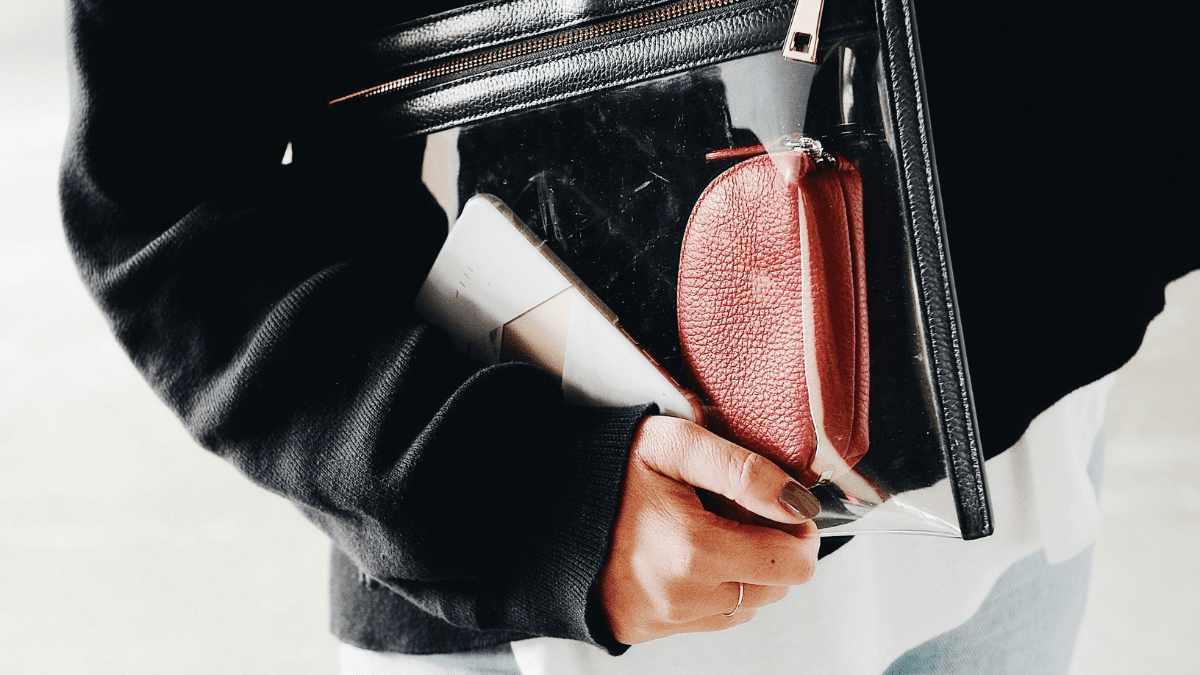 Femme portant un sac transparent avec un porte-monnaie et un téléphone pour faire une planification de publocation Instagram